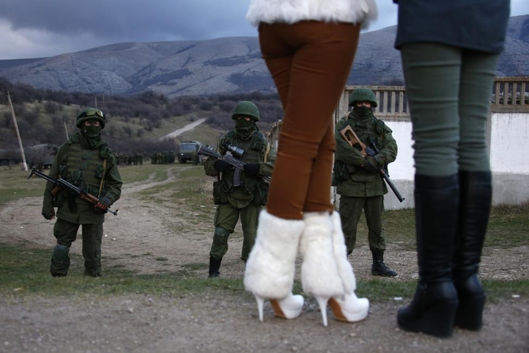 fot. Thomas Peter / Reuters / 5 marca 2014  Perewalne, Ukraina  Lokalne kobiety patrzą na uzbrojonych mężczyzn (prawdopodobnie rosyjskich żołnierzy), zbierających się nieopodal ukraińskiej bazy wojskowej w Perewalnym.